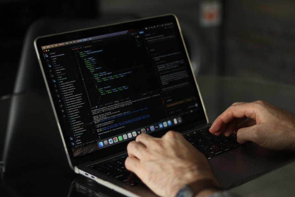 Close-up of a computer screen displaying a code editor with lines of HTML, CSS, and JavaScript code in various colours such as red, green, blue, and purple. The screen is slightly blurred, emphasizing